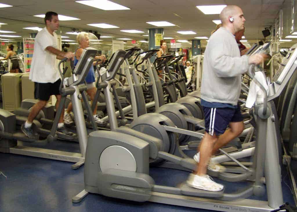 men and women at the gym doing cardio exercises on ellipticals