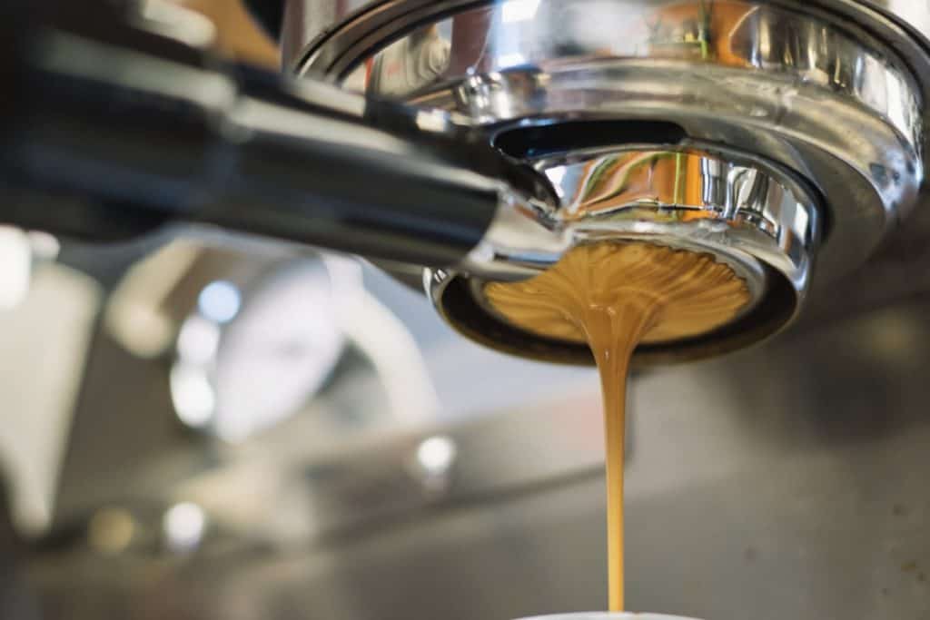 A picture of a shot of espresso flowing from an open portafilter. 