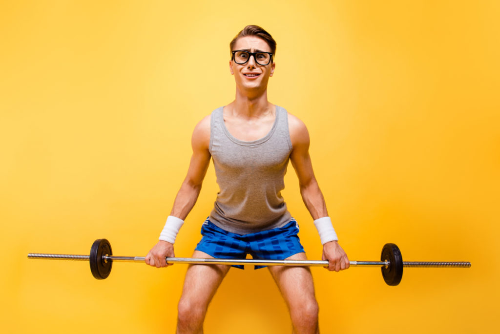 It seems I'm not in shape! Portrait of masculinity man with a confused and puzzled face can not lift a heavy barbell isolated on bright yellow background taking D-bal to gain muscle