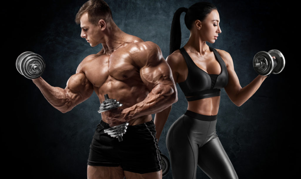 Sporty couple workout with dumbbells. Muscular man and woman showing muscles obtained from supplementing with D-bal