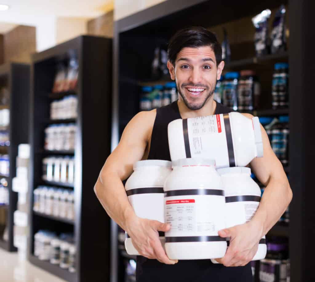 a young sporty male holding 4 bottle's of protein