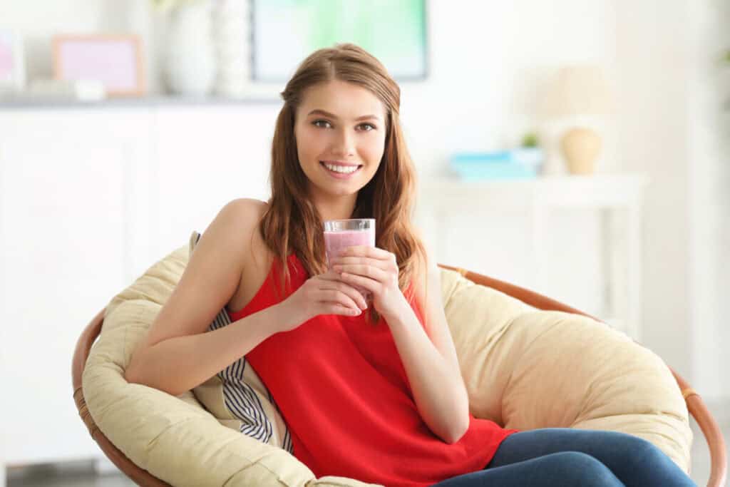 Weight loss concept. Beautiful young woman drinking healthy delicious smoothie at home