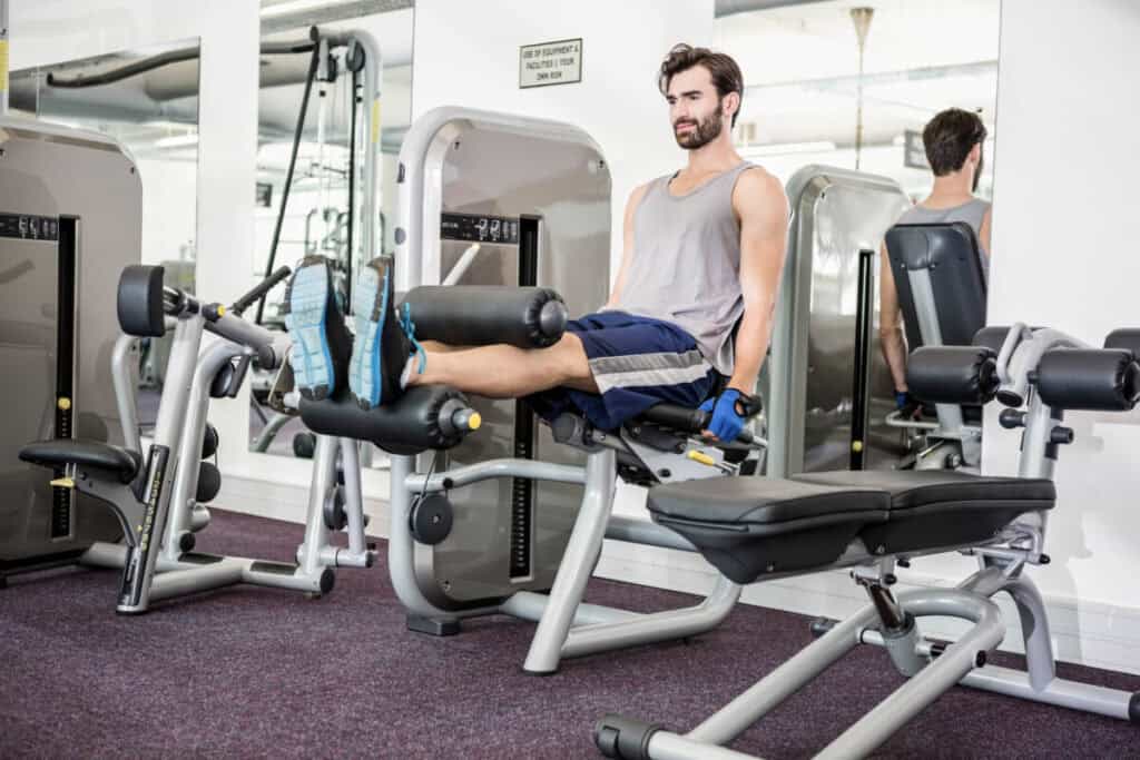 Focused man using weights machine for legs at the gym