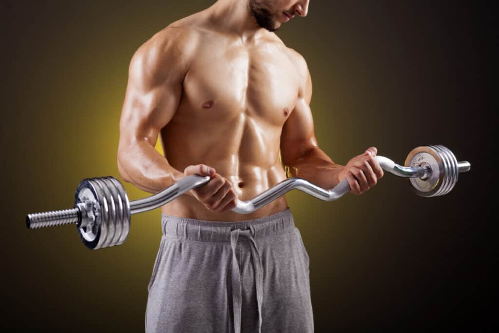 Fitness man lifting weights with curl bar against dark background