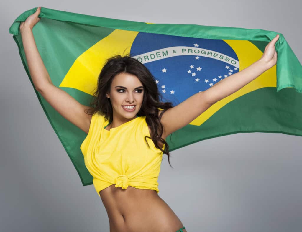 Portrait of beautiful brazilian fitness influencer holding the brazilian flag.