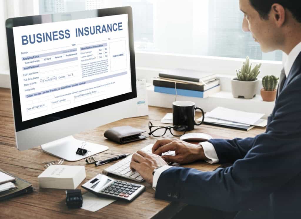 A man in a suit sitting at a desk looking at Athletic Trainer Liability Insurance