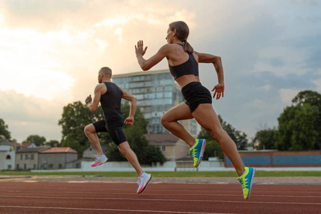 a man and woman running on a track wearing running shoes and workout gear