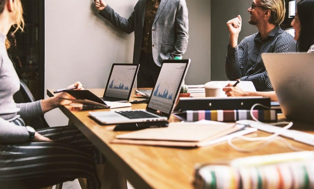 A group of people sitting around a conference table, sitting for too long can cause spider veins.