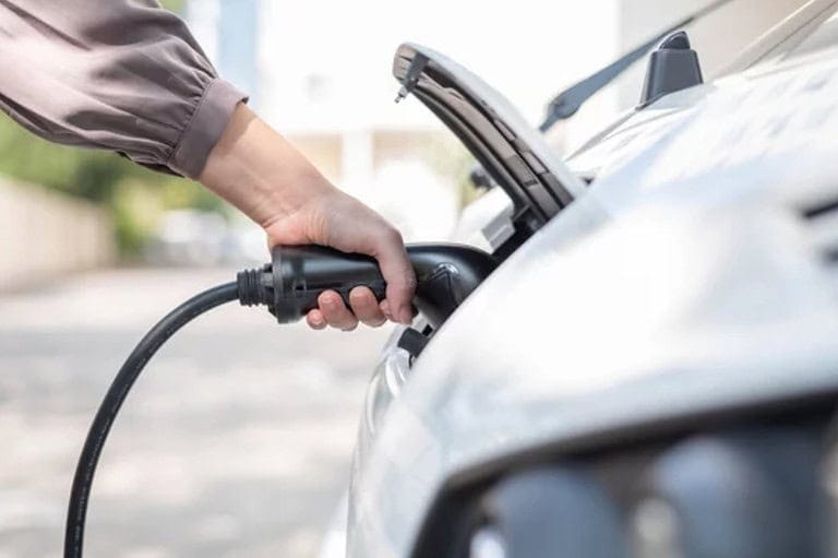 shot of a lady's hand with EV charger charging a vehicle