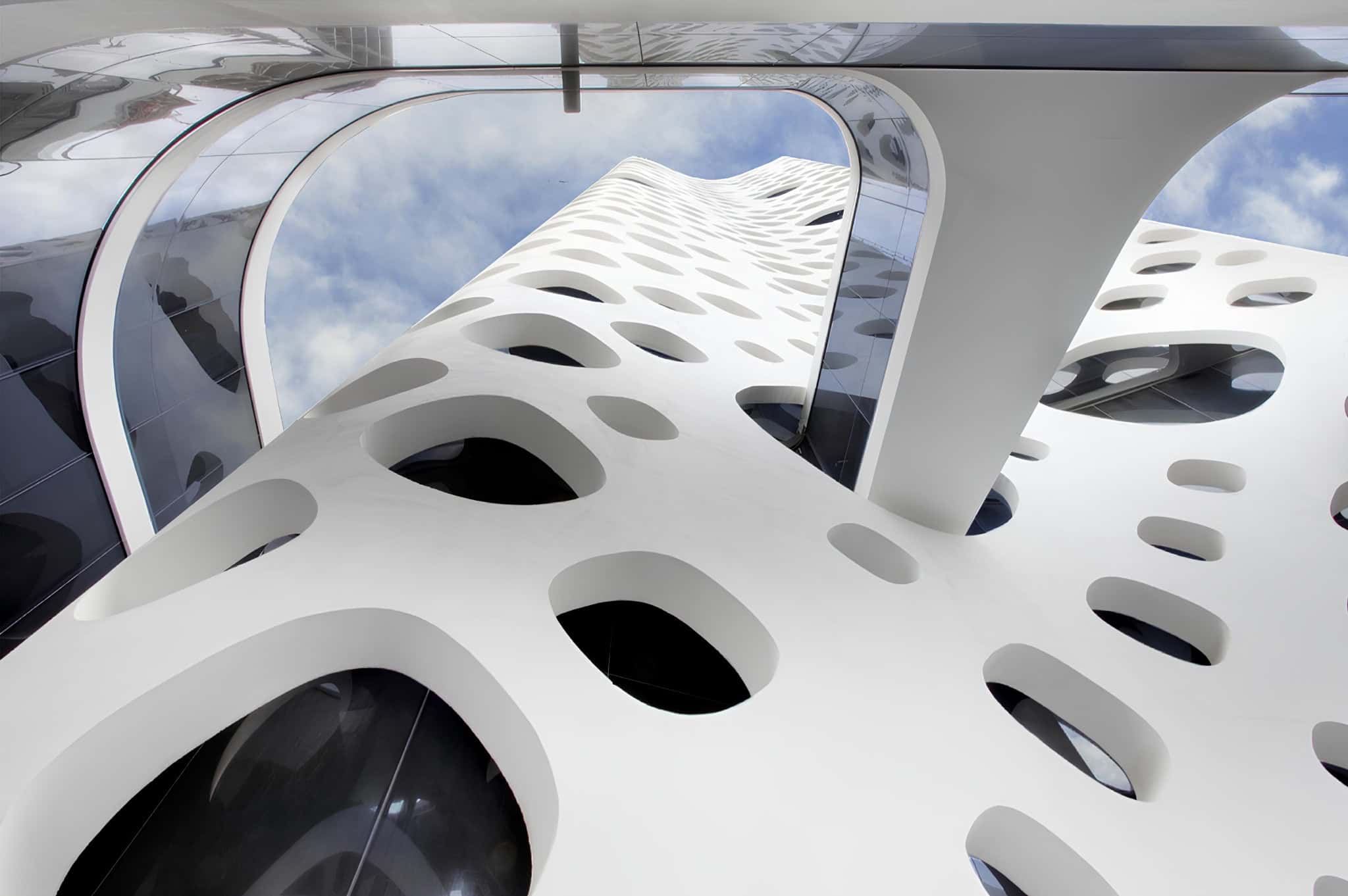 Futuristic architectural building with innovative white perforated facade and sleek curved design, showcasing modern architecture and contemporary design elements.
