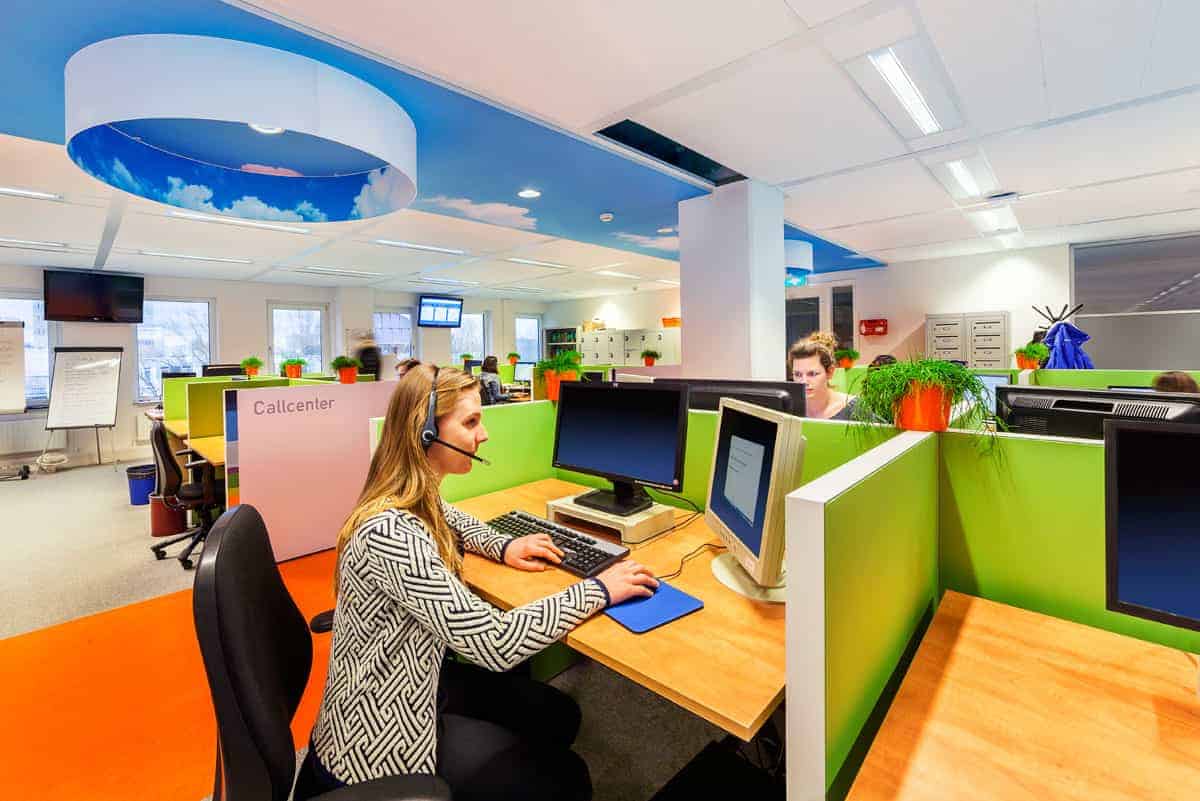 Modern office workspace with colorful cubicles, friendly staff, and innovative interior design, showcasing contemporary architecture and functional work environment.