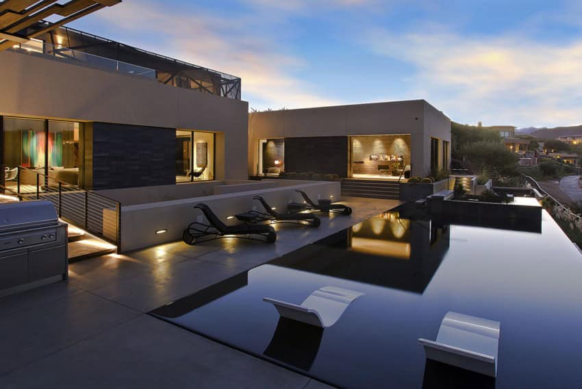 Luxury modern rooftop pool with sleek lounge chairs and contemporary architecture during sunset.