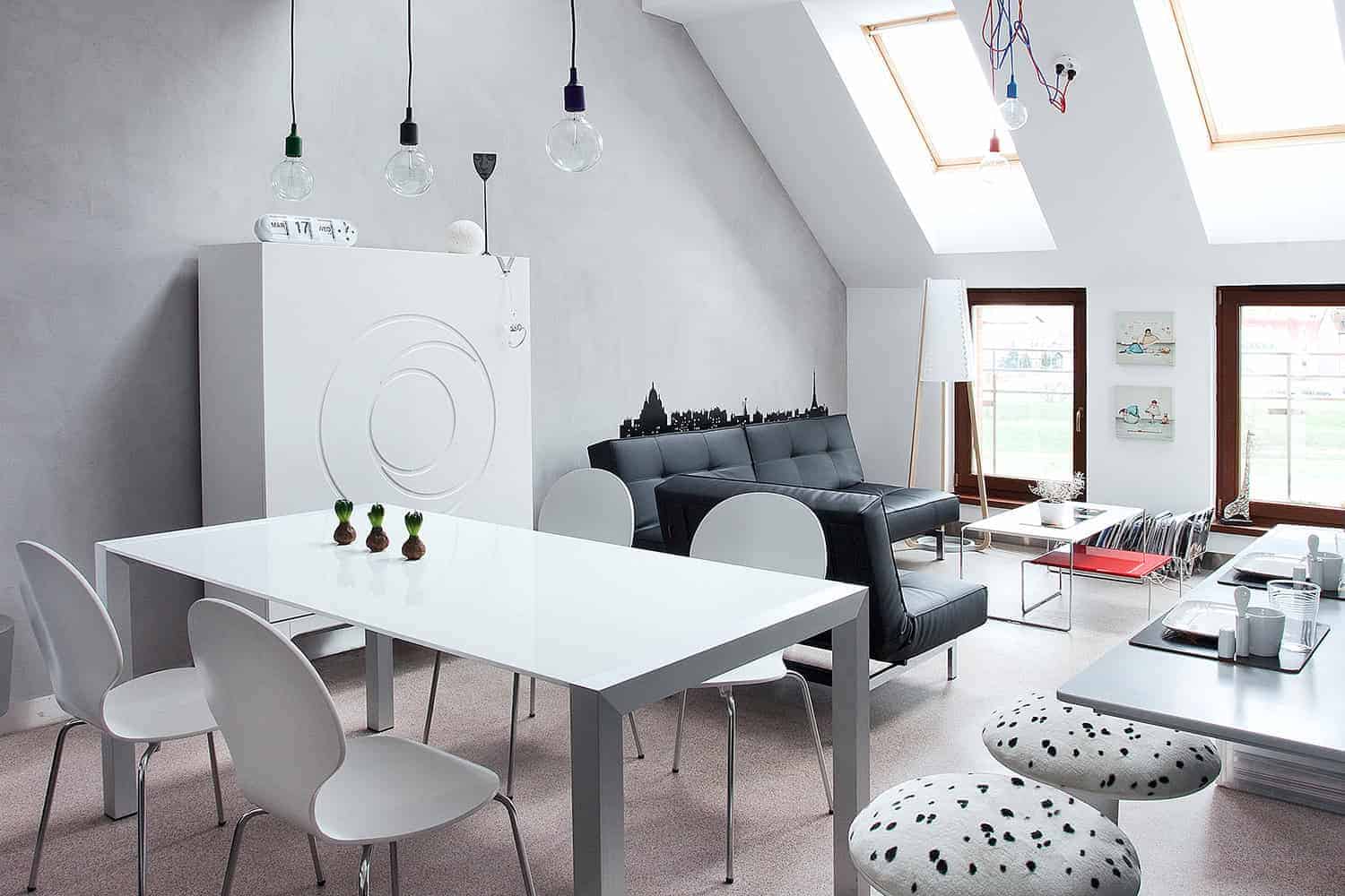 Contemporary attic living room with modern furniture, skylights, and minimalist decor, featuring black and white color scheme and stylish natural light design.
