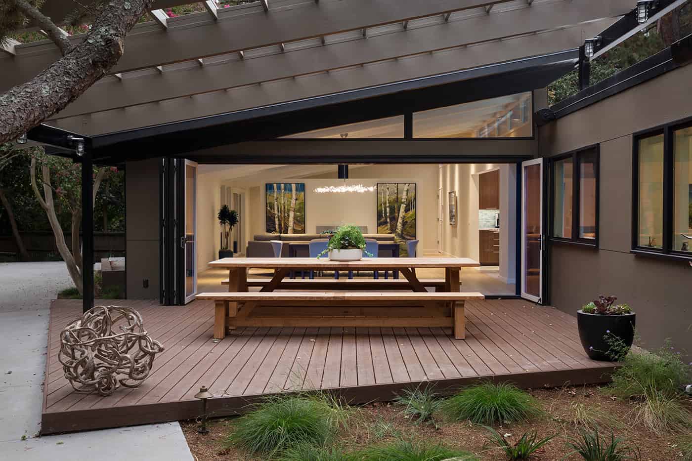 Contemporary outdoor living space with a wooden deck and glass sliding doors, blending indoor and outdoor design. Modern patio ideal for relaxing and entertaining with stylish decor.
