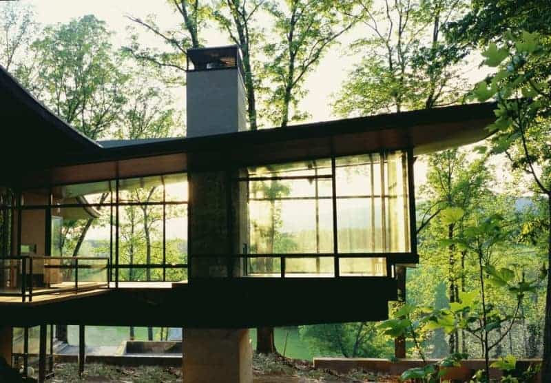 Modern glass house architecture with expansive windows and natural surroundings emphasizing contemporary design and integration with nature.