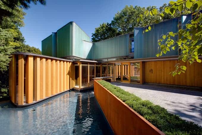 Modern architectural house with innovative design using natural wood and vibrant green metal exterior, surrounded by lush greenery, showcasing contemporary architecture and exterior design.