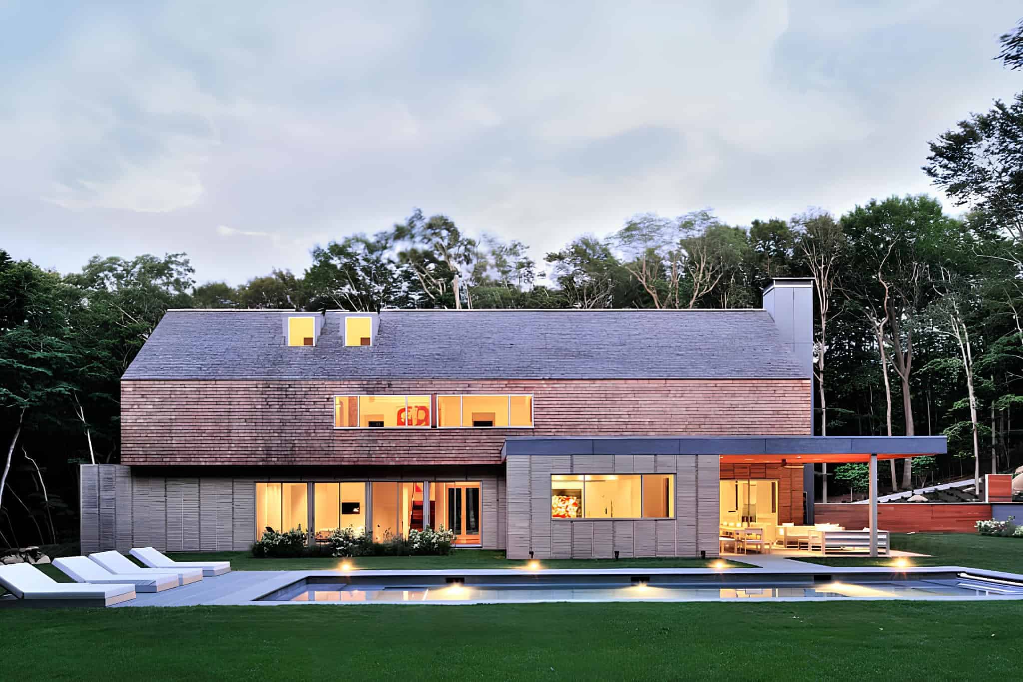 Sleek modern house with wooden and concrete accents, large glass windows, outdoor pool, and lush lawn surrounded by trees, showcasing contemporary architectural design and innovative residential concepts.