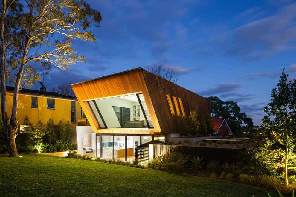 Futuristic modern house with striking angular architectural design, illuminated at dusk amidst landscaped garden, showcasing innovative residential architecture and contemporary design elements.