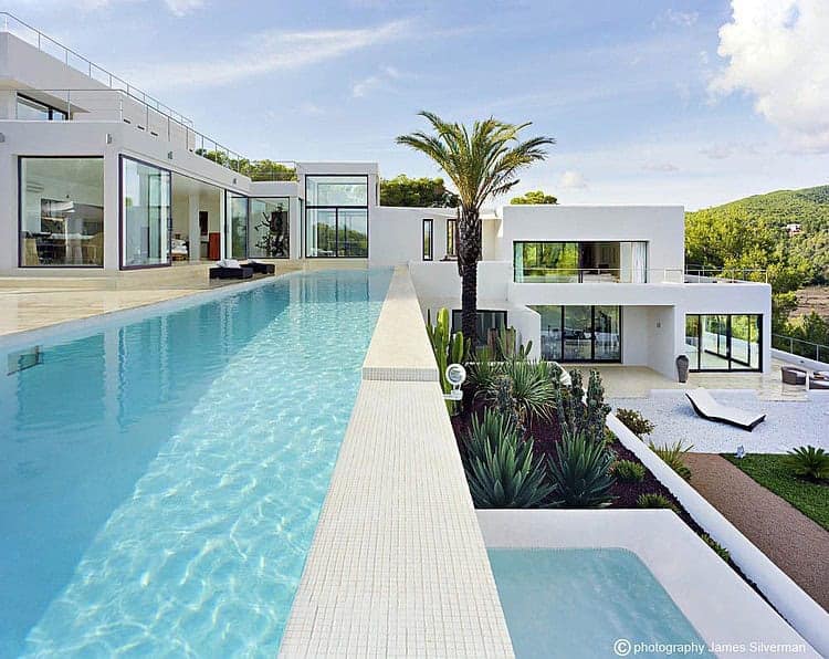 Luxury modern villa with an infinity pool and sleek white architecture, lush landscaping, and scenic views, perfect for contemporary outdoor living and relaxation.