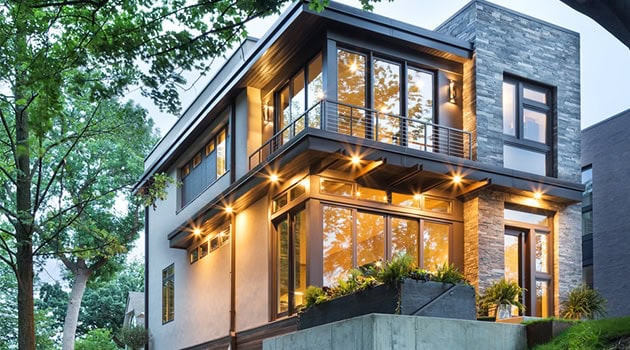 Modern luxury house with extensive glass windows and stone accents, showcasing contemporary architecture and innovative design.