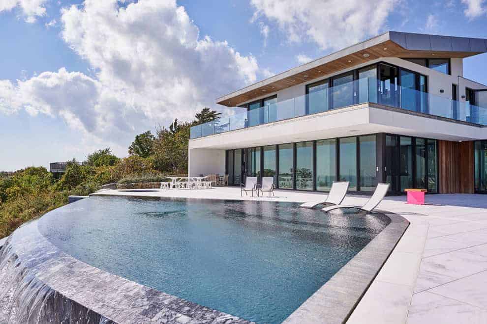 Modern luxury house with infinity pool and contemporary architecture, featuring large glass windows and sleek design elements for upscale living.