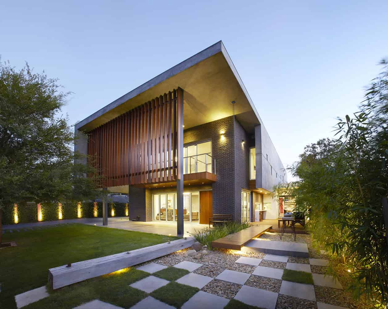 Contemporary modern house with sleek architectural design, large windows, wooden accents, and outdoor patio, surrounded by landscaped garden, ideal for luxury residential architecture.