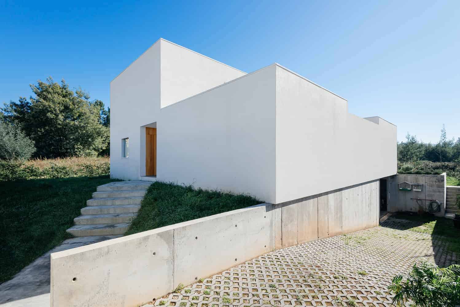 Contemporary minimalist white house with clean geometric lines, modern architecture, and unique cubic design. Perfect example of sleek, modern residential architecture with outdoor stairs and landscaped surroundings.