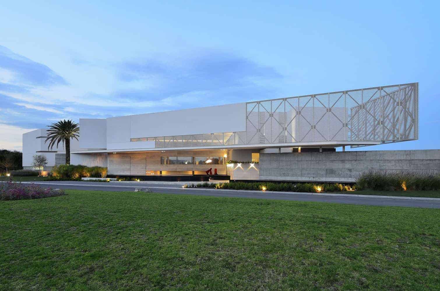 Contemporary modern house with sleek white architecture, clean lines, and unique geometric facade design, surrounded by manicured lawn and landscaped garden, showcasing minimalist luxury style.