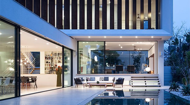 Modern contemporary house with sleek glass walls and stylish outdoor patio area, showcasing innovative architecture design and luxurious residential building concepts for modern living.