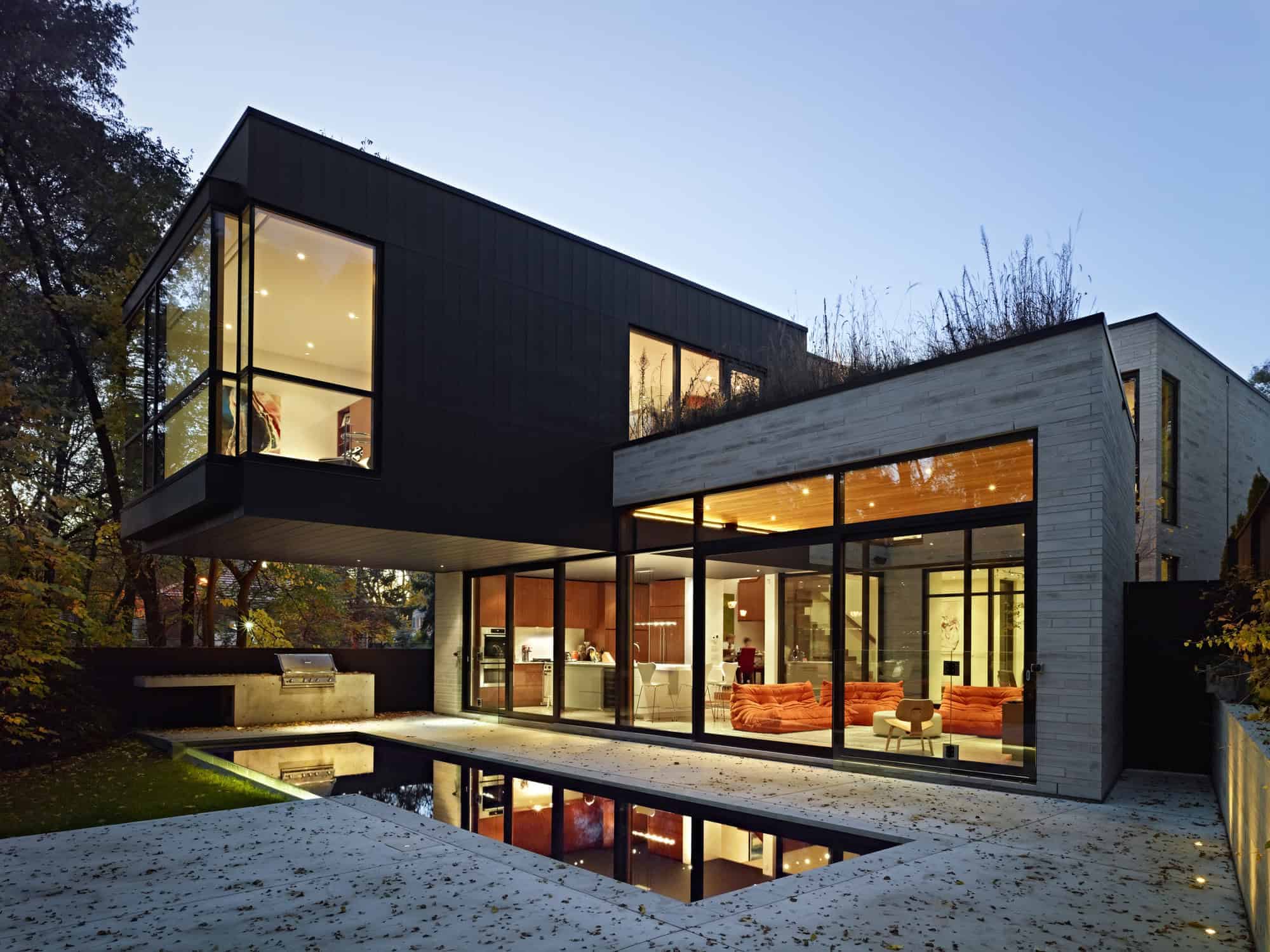 Modern contemporary house with large glass windows, sleek black and light wood exterior, innovative architectural design, and stylish indoor-outdoor living spaces.