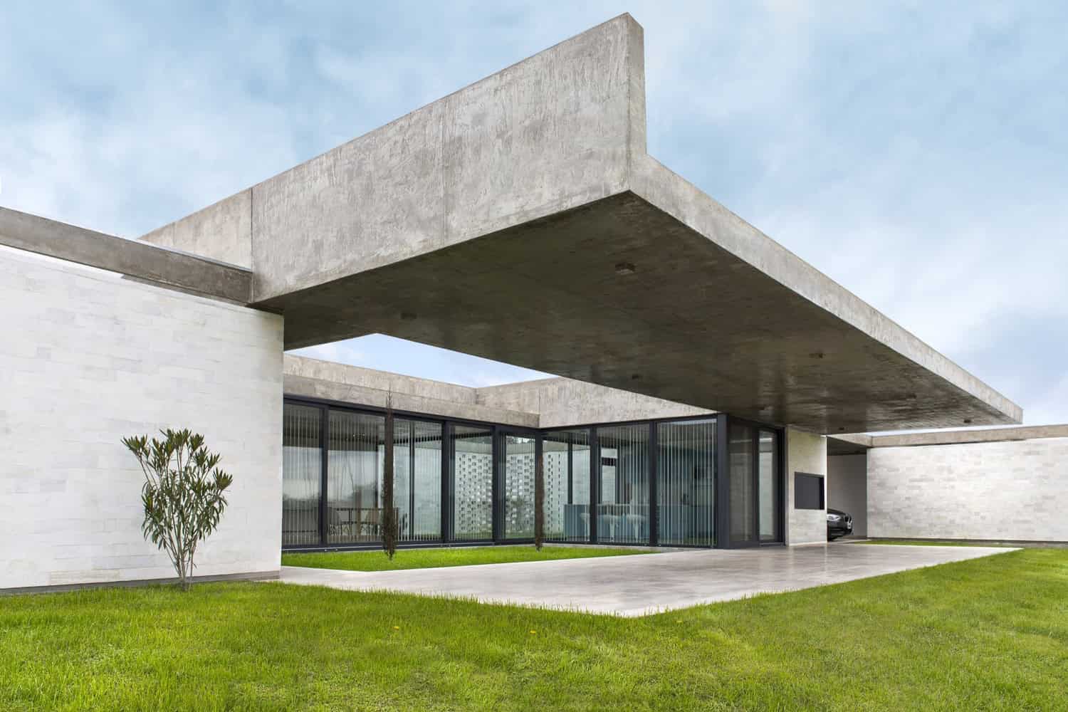 Sleek modern concrete architecture with clean lines and large glass windows, showcasing contemporary residential design and innovative use of materials.