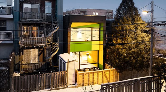 Colorful modern tiny house exterior with bold green and black accents, urban backyard setting, outdoor lighting, and contemporary architectural design elements.