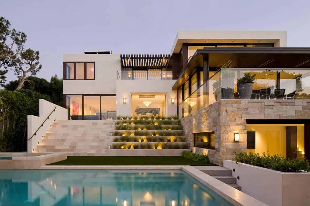 Luxury modern hillside mansion with sleek architectural design and expansive glass walls, featuring a swimming pool, outdoor living spaces, and contemporary landscaping.