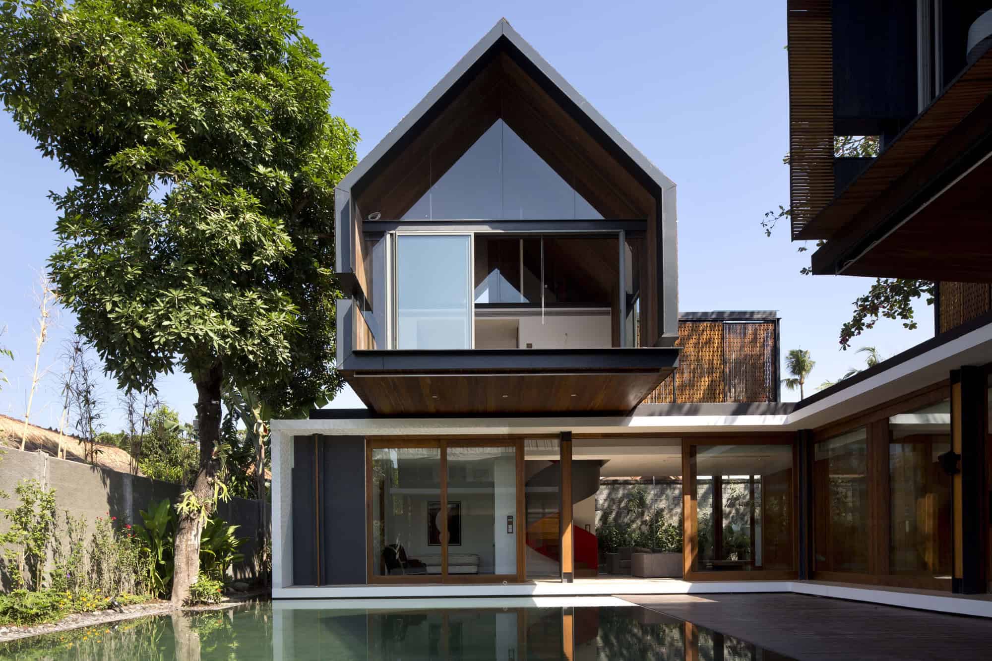 Contemporary modern house with striking architectural design, large glass windows and wooden accents, set in a lush garden with a reflecting pool for a harmonious, stylish living space.