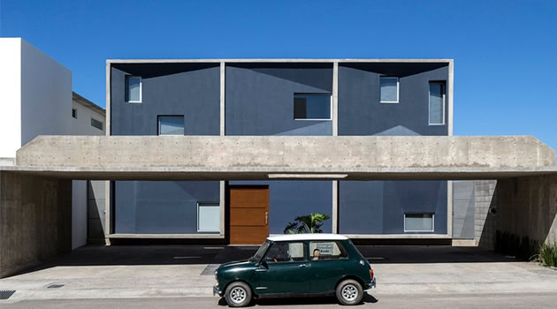Modern minimalist house with geometric design, sleek gray facade, and large windows, showcasing contemporary architecture and urban residential style.