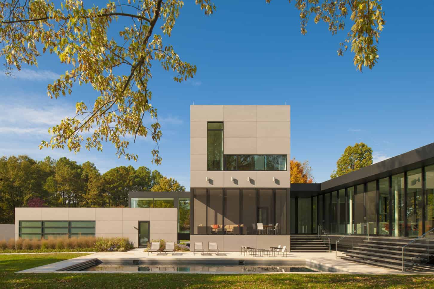 Modern contemporary house with sleek architectural design, large glass windows, and outdoor pool, surrounded by lush greenery and trees, perfect for luxury home architecture and design inspiration.