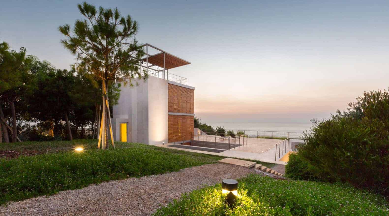 Modern seaside villa with sleek architectural design featuring clean lines, large glass windows, and natural wood accents in a serene coastal landscape.