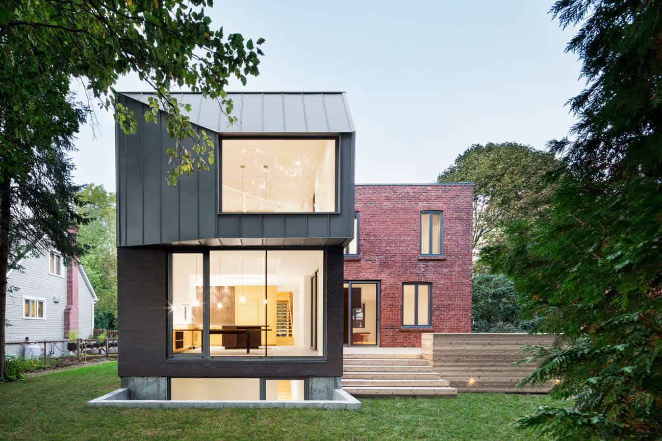 Modern contemporary house featuring large glass windows, sleek black and red brick exterior, and minimalist outdoor landscaping.