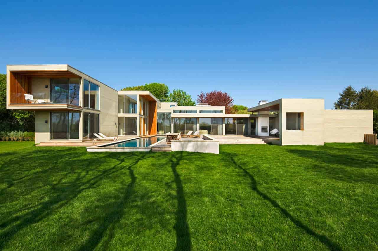 Modern luxury house with large glass windows, sleek concrete design, outdoor pool, and expansive green lawn, showcasing contemporary architecture and innovative residential design.