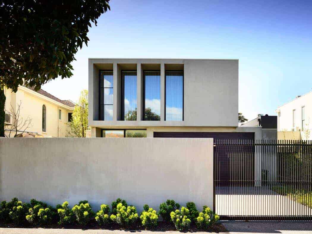 Modern minimalist house with clean lines and large glass windows, surrounded by a simple fence and lush greenery. Perfect example of contemporary architecture and stylish home design.