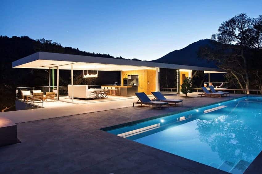 Modern luxury house with a stunning outdoor pool and contemporary open-plan living area surrounded by mountain scenery. Perfect for stylish outdoor entertainment and relaxation.