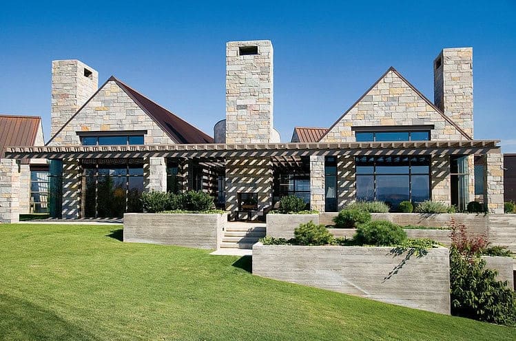 Contemporary modern house with stone accents, large glass windows, and a landscaped front yard.