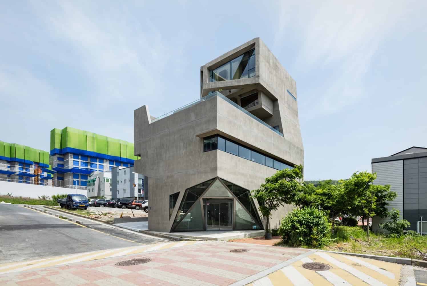 Futuristic modern concrete building with geometric design elements and large glass windows, showcasing innovative architecture and contemporary style.