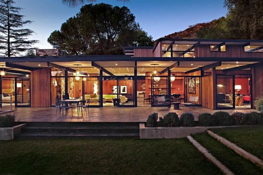 Modern glass house with wooden accents and outdoor patio, showcasing contemporary architecture and innovative design.