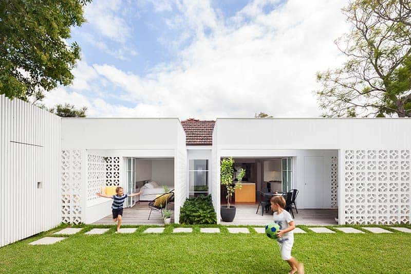Modern minimalist backyard home design with open living spaces and white decorative wall panels, ideal for family outdoor activities and contemporary architecture.
