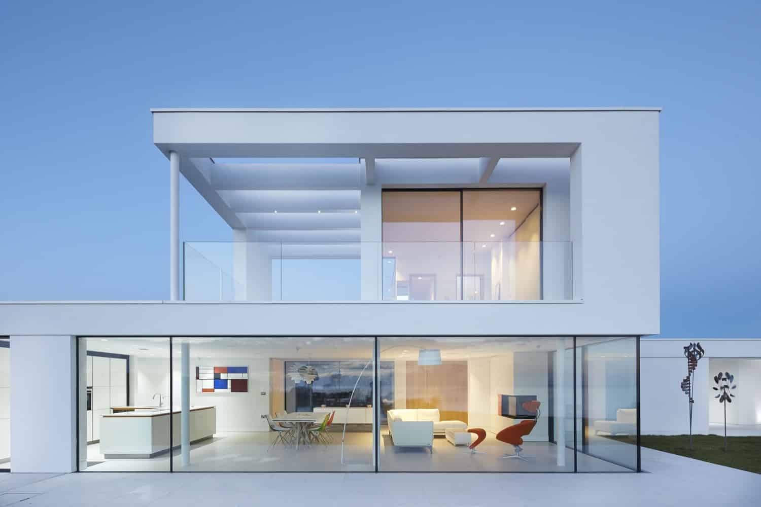 Modern minimalist white house with large glass windows and open-concept living space, showcasing contemporary architecture, sleek design, and stylish interior decor.