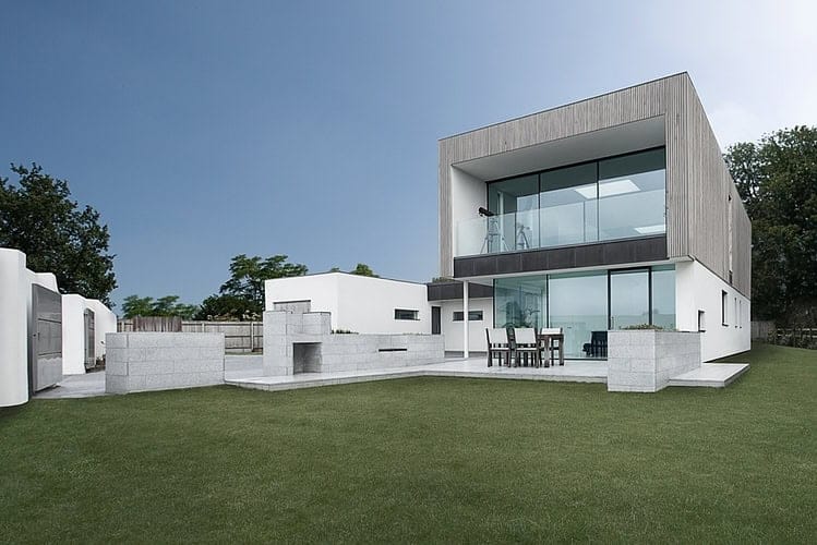 Modern minimalist house with large glass windows and a sleek outdoor patio, showcasing contemporary architecture and innovative design elements.