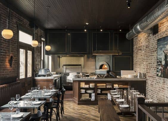 Modern industrial-style restaurant interior with exposed brick walls, black cabinetry, and wood accents, perfect for contemporary dining experiences.