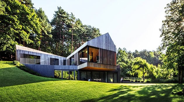 Stunning modern architectural house with a unique design blending with lush green landscape and forest surroundings, showcasing innovative architecture art and contemporary design principles.