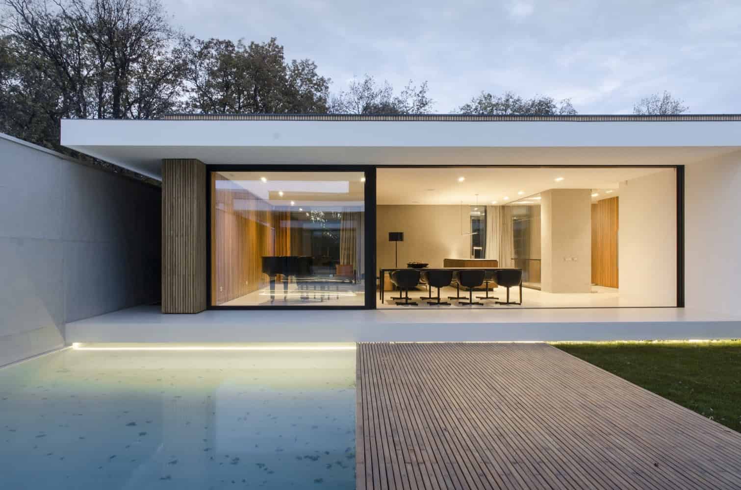 Modern minimalist house with large glass windows showcasing sleek interior design and contemporary architecture.